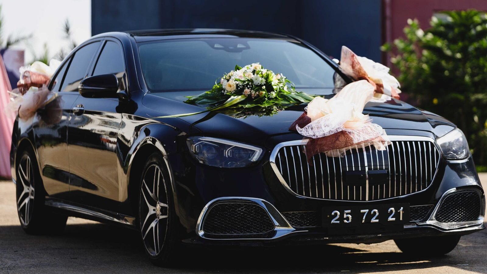 Black luxury car decorated with white flowers and ribbon for a wedding
