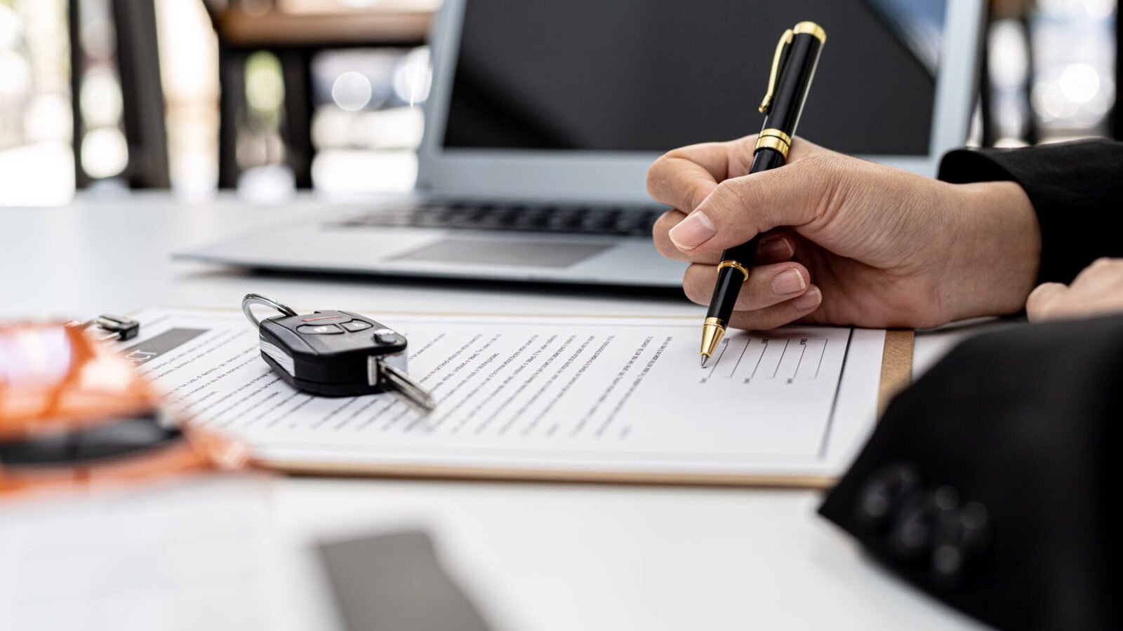 Signing a car rental contract with the car key on the desk